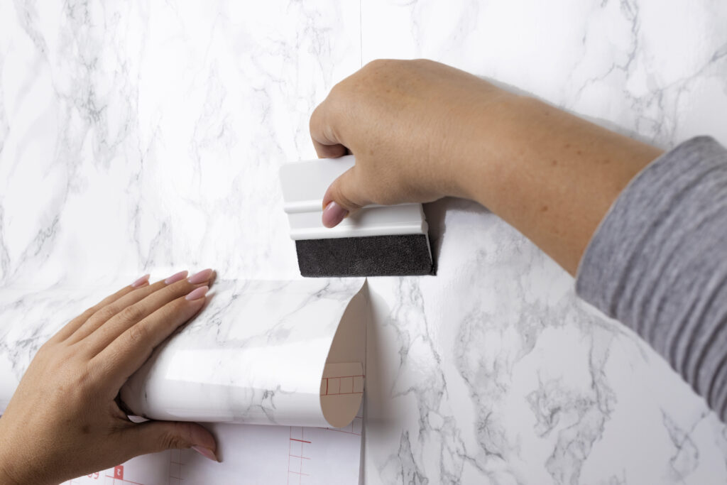 photo représentant la pose d'un papier peint sur un mur blanc